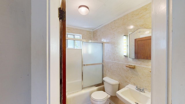 full bathroom with sink, toilet, bath / shower combo with glass door, and tile walls