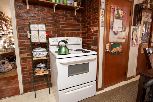 kitchen featuring white range with electric cooktop and brick wall