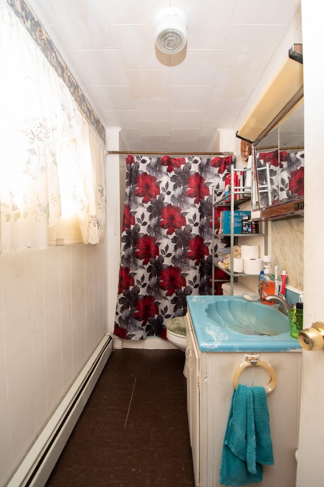 bathroom with toilet, vanity, and a baseboard heating unit