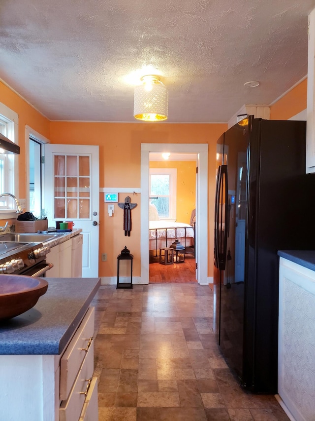 599 Plains Rd, Hollis, ME 04042 - kitchen with black fridge with ice dispenser, white cabinets, baseboards, dark countertops, and a textured ceiling