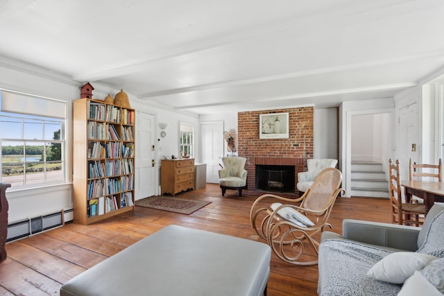 living room featuring beam ceiling, light hardwood / wood-style flooring, a baseboard radiator, and a brick fireplace