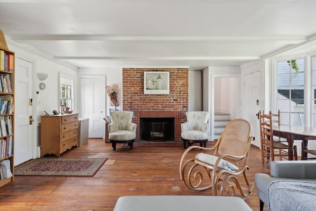 living room featuring hardwood / wood-style floors, beam ceiling, and a brick fireplace