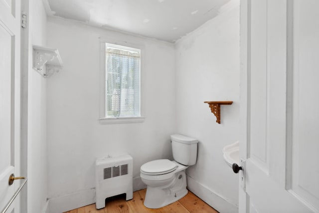 bathroom with radiator heating unit, toilet, and hardwood / wood-style floors