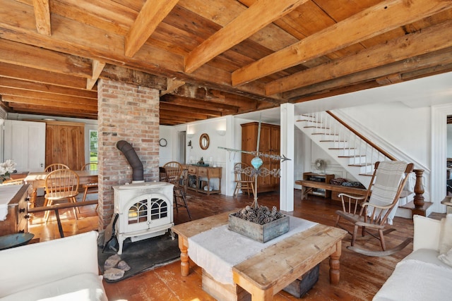 living room featuring beamed ceiling, hardwood / wood-style flooring, a wood stove, and wood ceiling