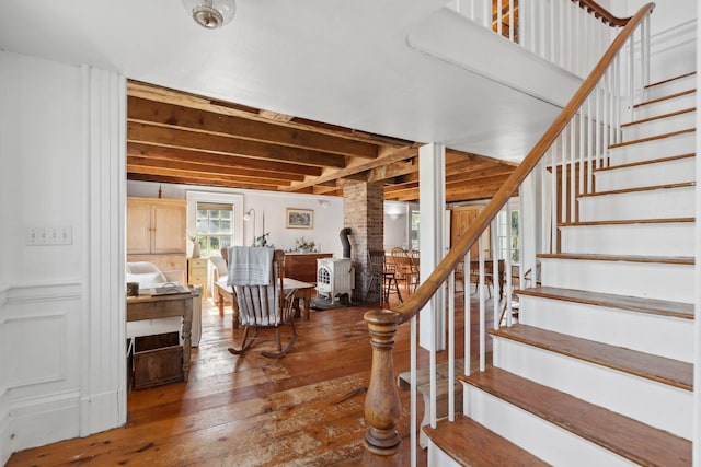 stairway with a wood stove and hardwood / wood-style floors