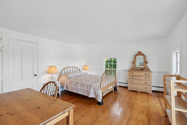 bedroom featuring hardwood / wood-style flooring and a baseboard heating unit