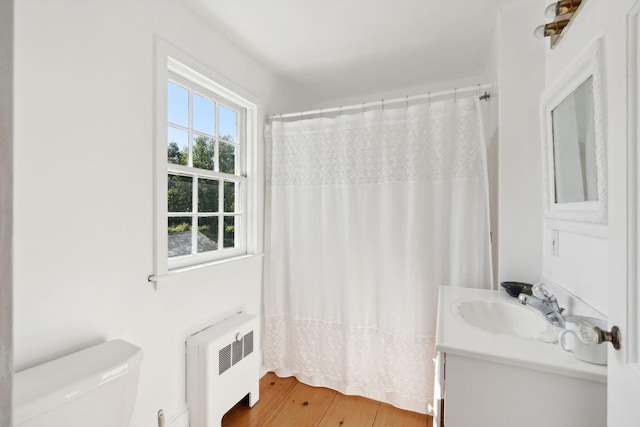 bathroom featuring radiator, vanity, hardwood / wood-style flooring, toilet, and curtained shower