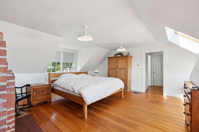 bedroom with hardwood / wood-style flooring and lofted ceiling with skylight