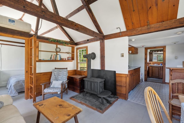 living room with lofted ceiling with beams and a wood stove