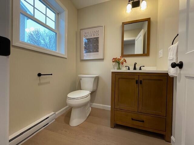 bathroom featuring toilet, vanity, a baseboard radiator, and hardwood / wood-style flooring