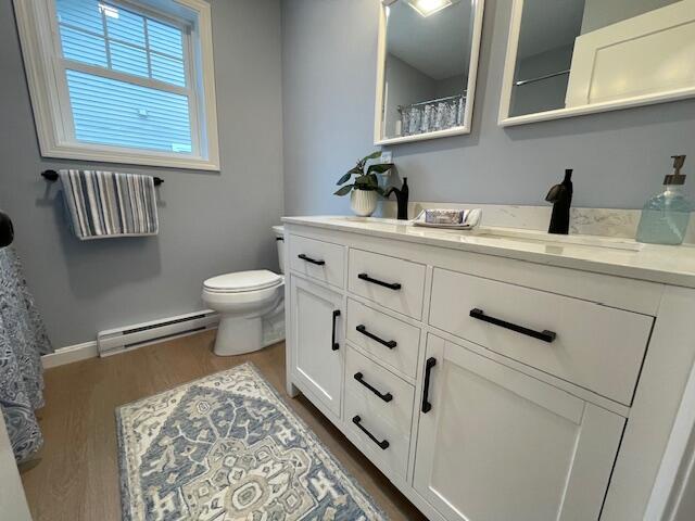 bathroom with vanity, hardwood / wood-style flooring, toilet, and baseboard heating