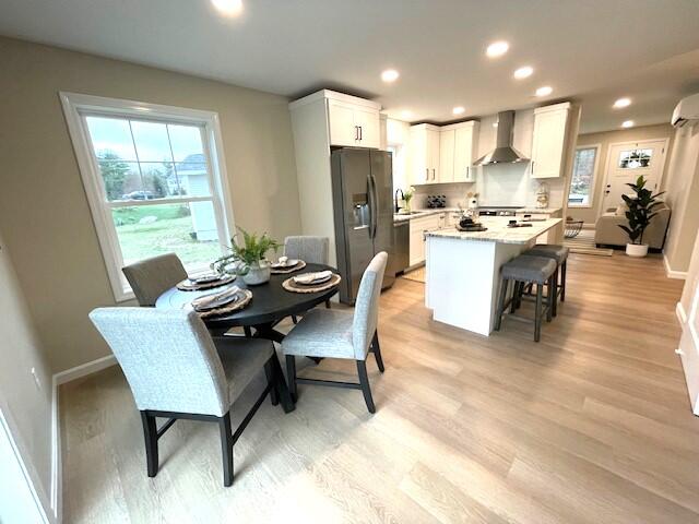 dining room featuring an AC wall unit, sink, and light hardwood / wood-style floors