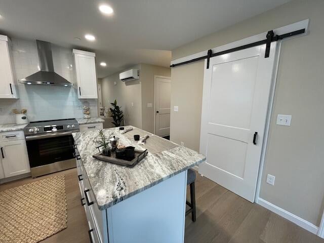 kitchen featuring white cabinets, a barn door, stainless steel range with electric stovetop, and wall chimney exhaust hood