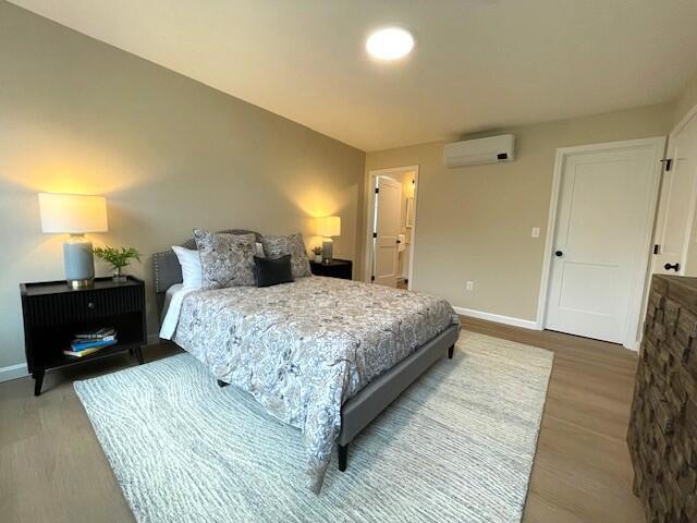 bedroom featuring hardwood / wood-style floors and a wall unit AC