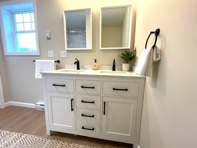 bathroom featuring vanity, hardwood / wood-style flooring, and a baseboard heating unit