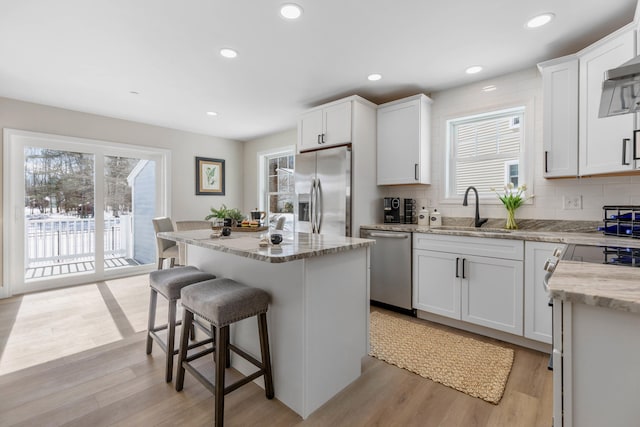 kitchen featuring stainless steel appliances, a center island, light wood-style floors, and a kitchen bar