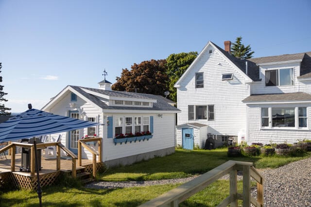 back of property featuring an outbuilding, a yard, and a wooden deck