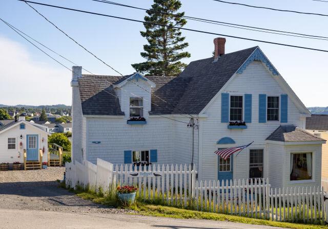 16 Monument St, Lubec, ME 04652 - view of front facade with a chimney, a fenced front yard, and roof with shingles
