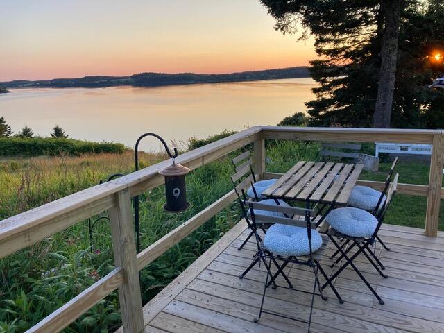 deck at dusk featuring a water view