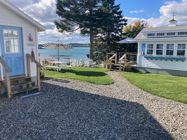 view of yard with entry steps and a deck with water view