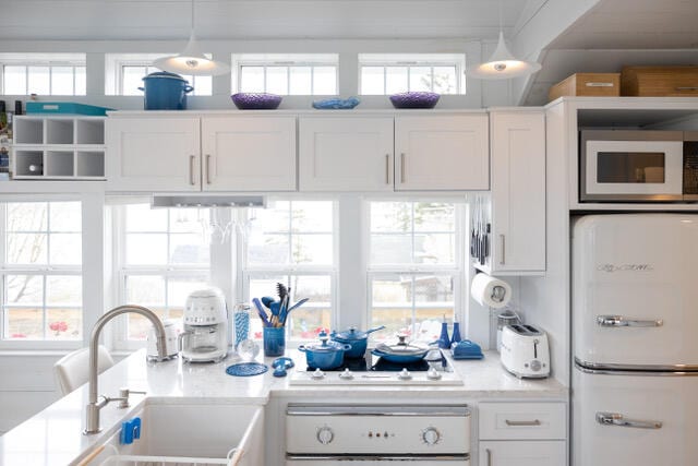 kitchen featuring light countertops, white appliances, a sink, and white cabinetry