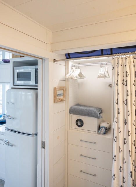 kitchen featuring built in microwave, wood walls, and white refrigerator