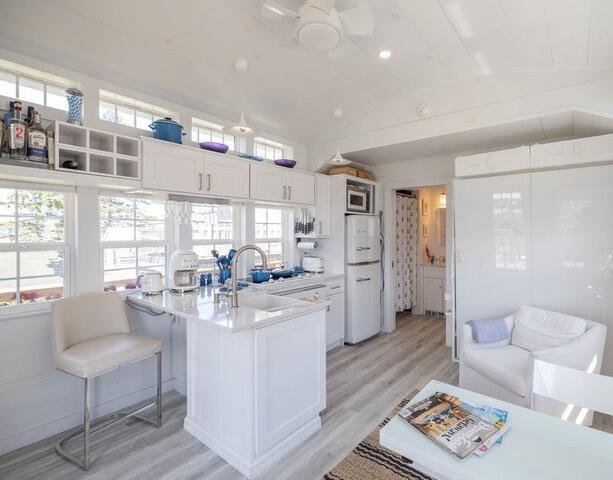 16 Monument St, Lubec, ME 04652 - kitchen featuring lofted ceiling, light wood-style flooring, stainless steel microwave, light countertops, and white cabinetry