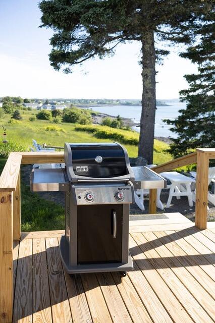 deck with a water view and area for grilling