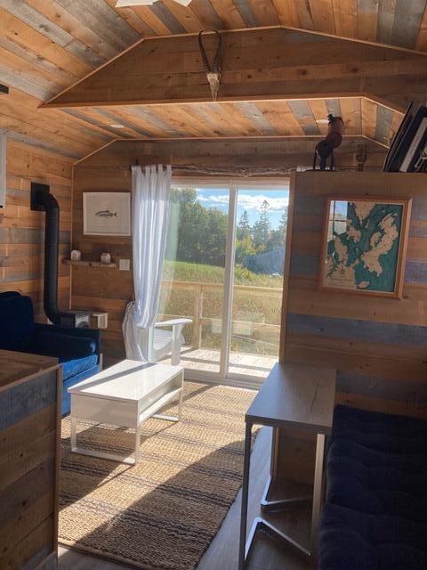 16 Monument St, Lubec, ME 04652 - living area with wooden walls, vaulted ceiling, wood ceiling, and a wood stove