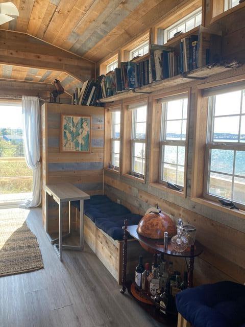 sitting room with wood walls, a water view, wood finished floors, wood ceiling, and vaulted ceiling