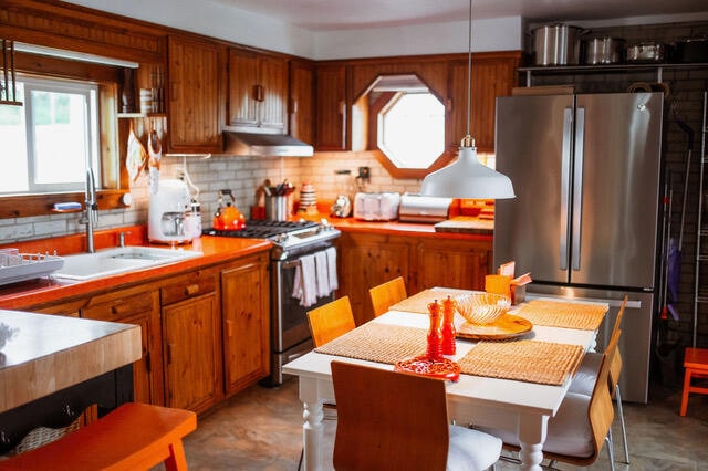 kitchen with appliances with stainless steel finishes, backsplash, a wealth of natural light, and under cabinet range hood