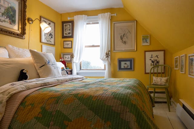 bedroom featuring multiple windows, a baseboard heating unit, and vaulted ceiling