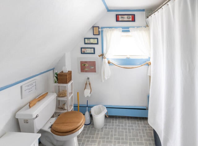 bathroom featuring toilet, baseboard heating, and lofted ceiling