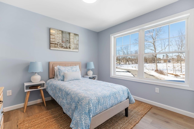 bedroom with multiple windows, baseboards, and wood finished floors