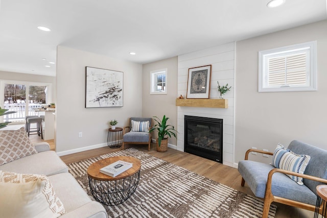 living area with recessed lighting, a large fireplace, baseboards, and wood finished floors