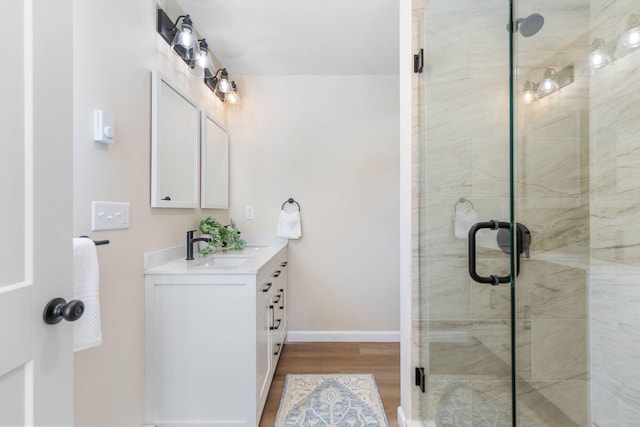 bathroom featuring a stall shower, vanity, baseboards, and wood finished floors