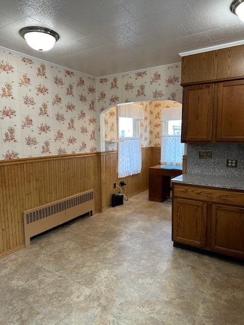 kitchen featuring backsplash, wooden walls, and radiator heating unit