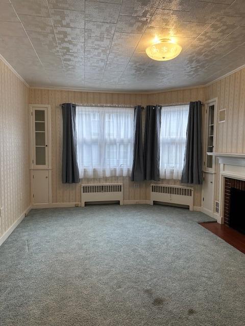 unfurnished living room with carpet, radiator heating unit, and a fireplace