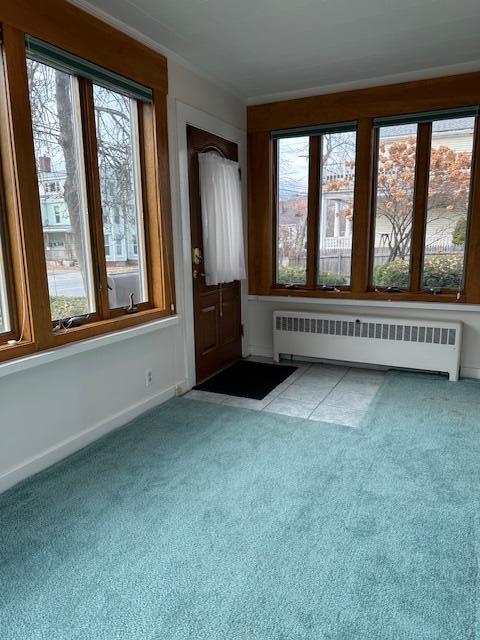 interior space featuring light carpet, radiator heating unit, and plenty of natural light