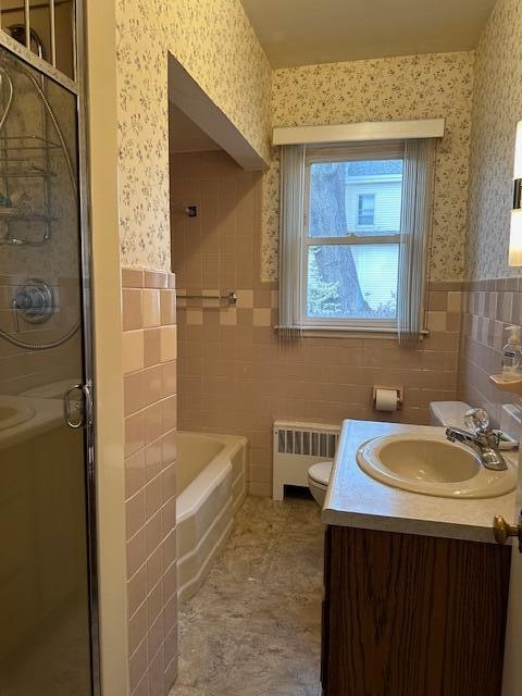 full bathroom with vanity, toilet, radiator, and tile walls