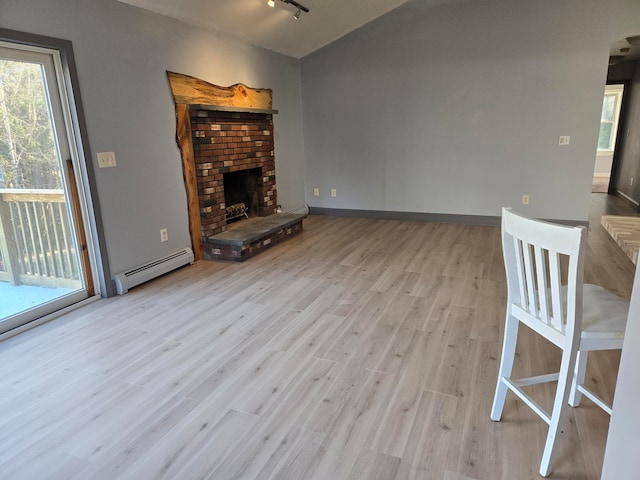 unfurnished living room with a brick fireplace, baseboard heating, and light hardwood / wood-style flooring