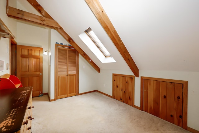 additional living space with vaulted ceiling with skylight and light colored carpet