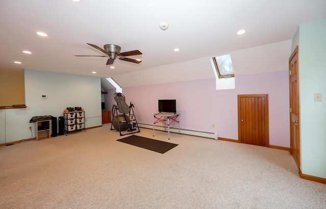 exercise area with baseboard heating, ceiling fan, vaulted ceiling with skylight, and light colored carpet