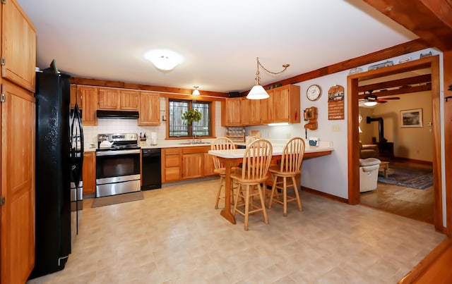 kitchen with sink, tasteful backsplash, stainless steel electric range, a kitchen bar, and black refrigerator