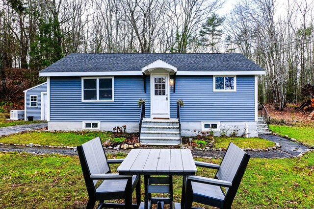 view of front facade with a shingled roof and a front yard