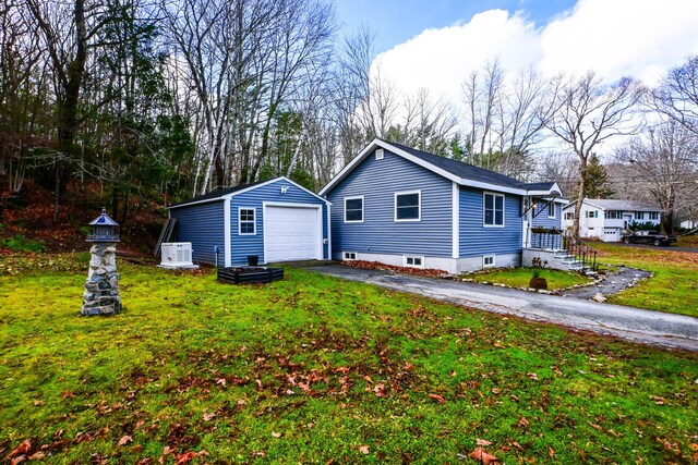 view of front of property with aphalt driveway, a front lawn, an outdoor structure, and a detached garage