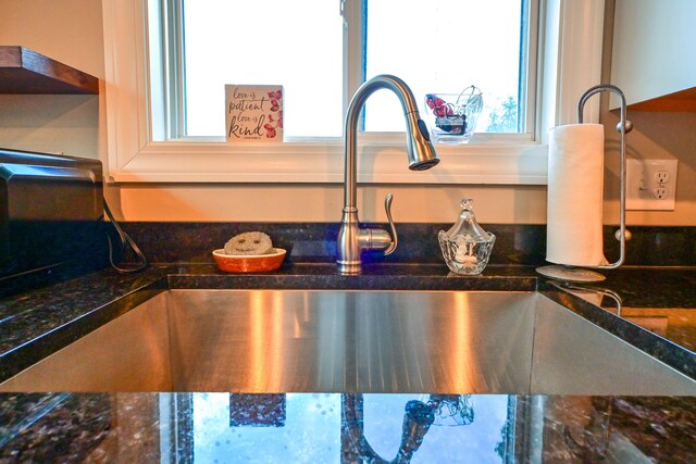 details featuring a sink and dark stone countertops