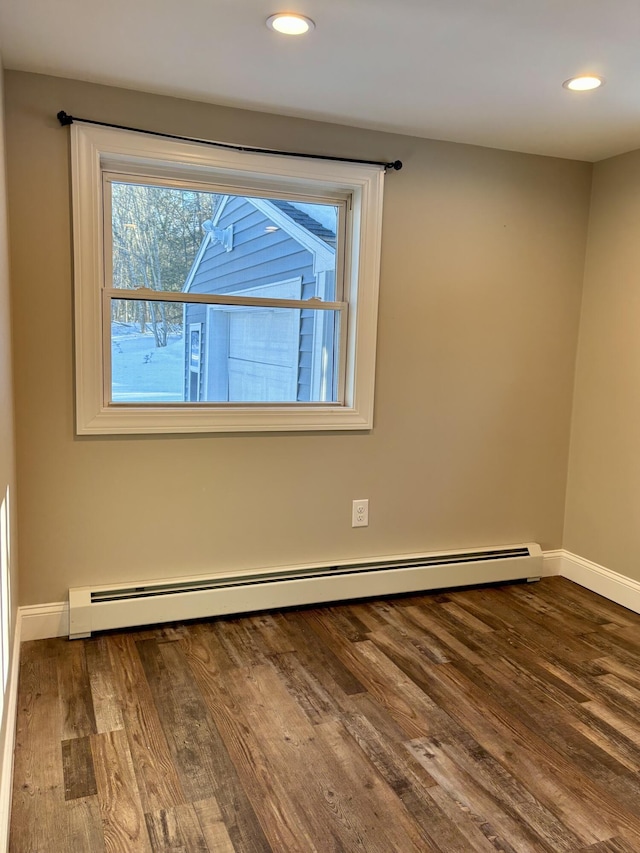 spare room with baseboards, baseboard heating, dark wood-type flooring, and recessed lighting