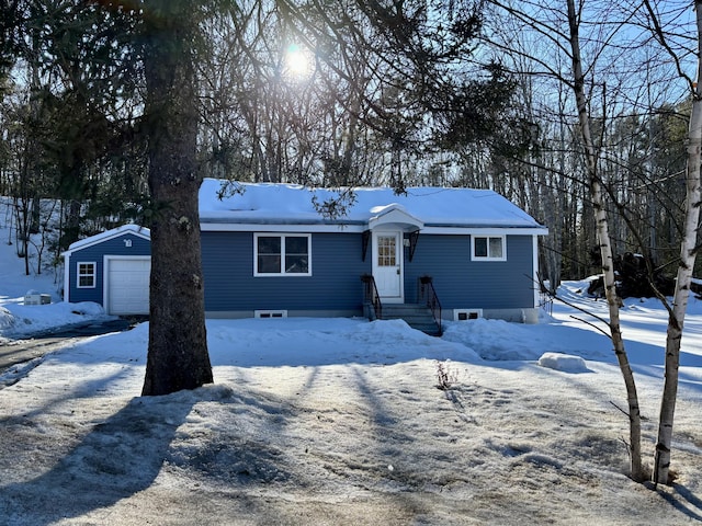 view of front of house with a detached garage and an outbuilding