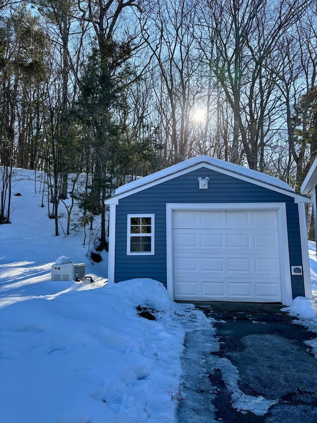 snow covered garage featuring a garage and driveway